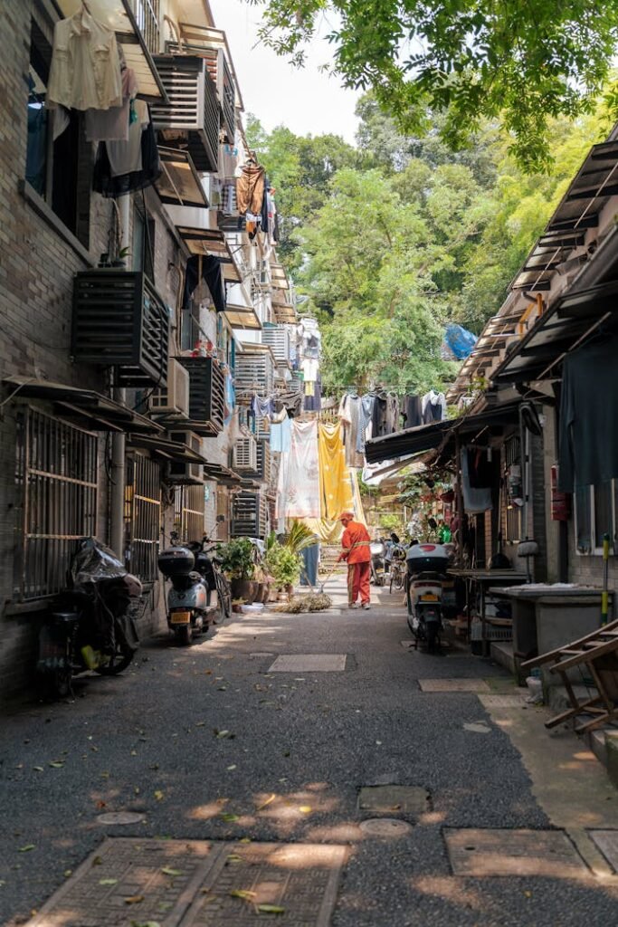 A narrow alleyway flanked by apartment buildings, featuring hanging laundry and mopeds, capturing everyday urban life.